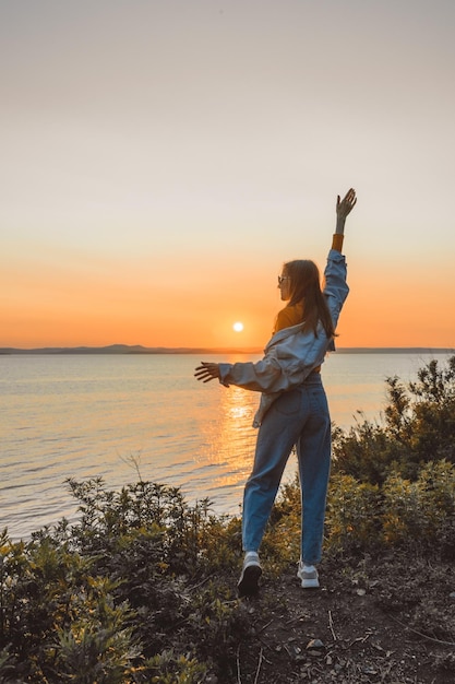 Foto ragazza felice in abiti eleganti in riva al mare durante il tramonto