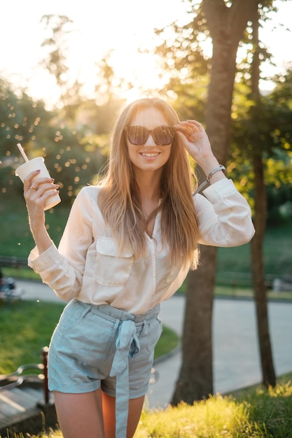 Happy girl in sunglasses drinking a milkshake and smiling