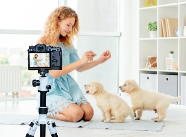 Happy girl teaching puppies to sit at home