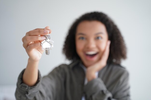 Happy girl tenant show keys of new house Closeup of hand with home key Real estate rental service