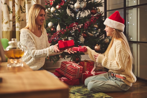 Happy girl unwrapping presents with mom at Christmas