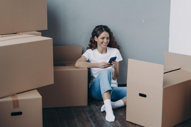 Happy girl uses phone apps choosing relocation service answers her mover online Easy moving day