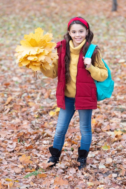 Photo happy girl walking in autumn park after school teen girl holding autumn leaves outdoors school holidays school education