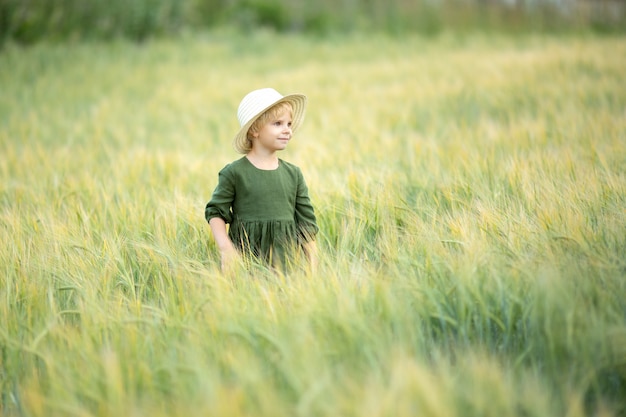 Happy girl walking in golden wheat, enjoying the life in the field. Nature beauty and field of wheat. Family outdoor lifestyle. Freedom concept. Cute little girl in summer field