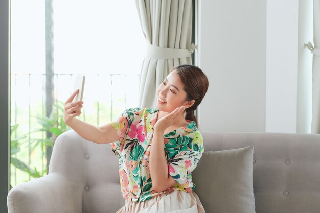 Happy girl waving hand using smartphone app enjoying online virtual chat video call with friends