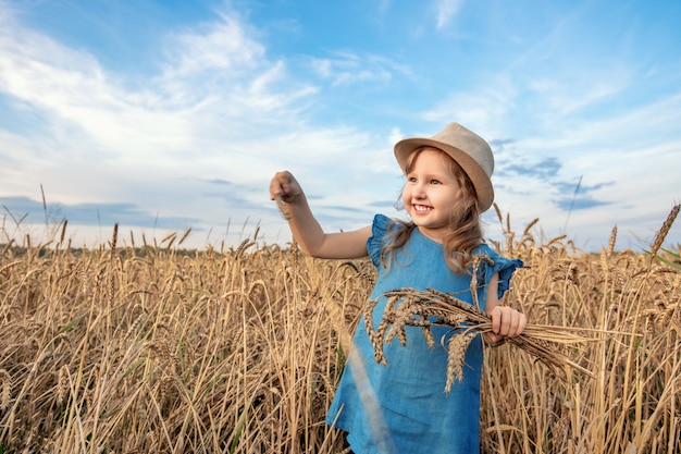 Happy girl in wheat field on warm and sunny summer evening.