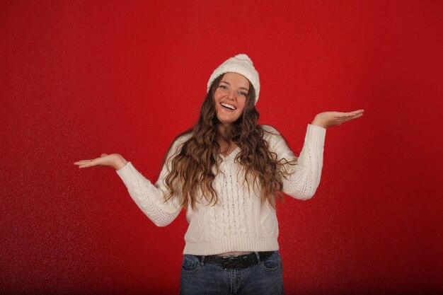 겨울 모자를 쓴 행복한 소녀와 인공 눈 배경에 청바지를 입은 니트 스웨터