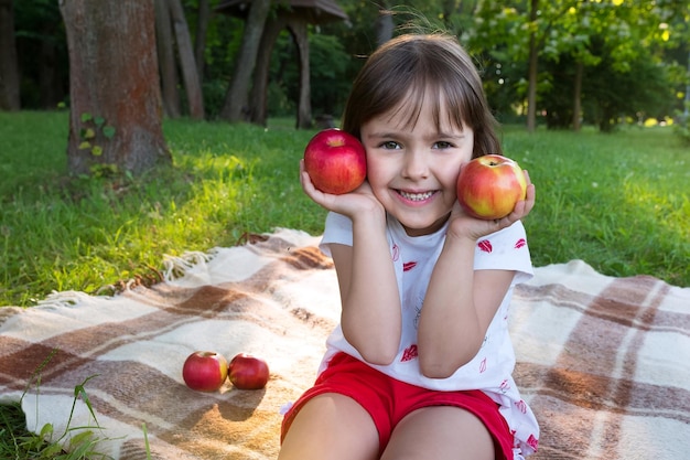 Happy girl with apples in her hands in the park