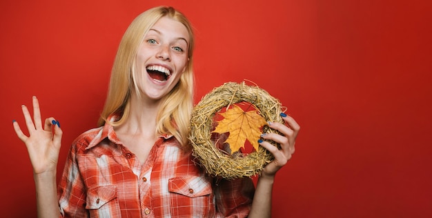 Happy girl with autumn wreath showing ok sign smiling woman in plaid shirt with decorative chaplet