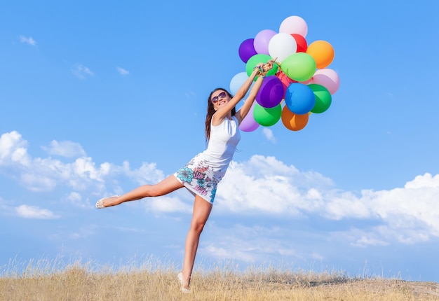 Happy girl with bunch of colorful air balloons