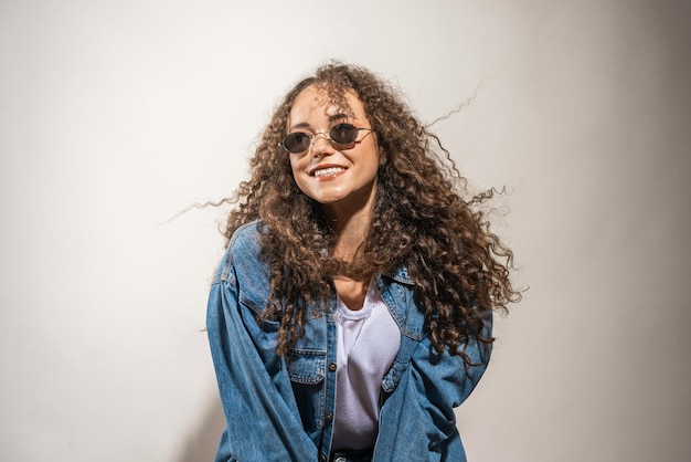 A happy girl with curly hair on a gray background A woman in a denim jacket