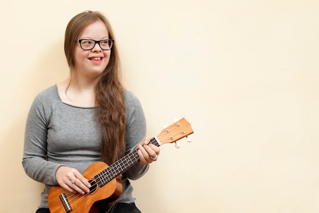 Photo happy girl with down syndrome holding guitar