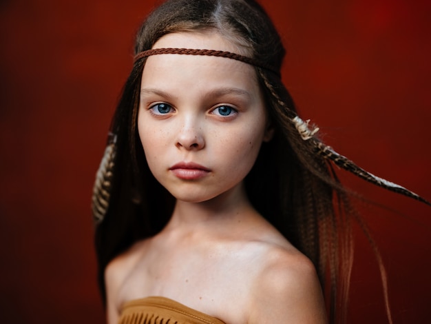 Happy girl with a feather in her hair aborigines indian tribe\
shaman red