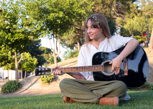 Ragazza felice con la chitarra divertendosi all'aperto