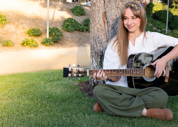 Foto ragazza felice con la chitarra divertendosi all'aperto