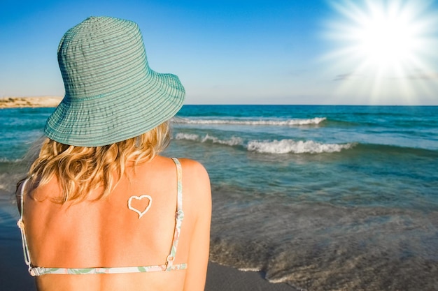 Happy girl with a heart on her back by the sea outdoors