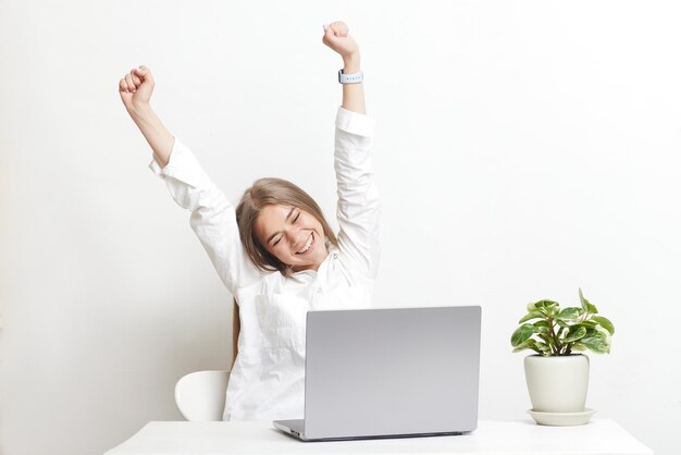 Happy girl with laptop rejoices on white background