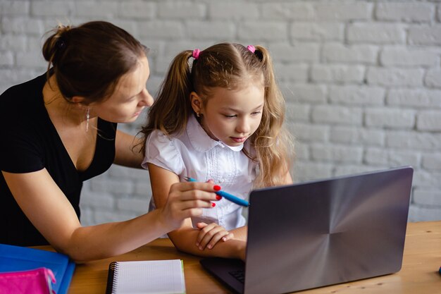 Foto ragazza felice con la madre che studia in linea a casa. concetto di tecnologia di apprendimento o istruzione online