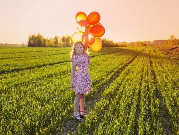 Happy girl with orange balloons outdoor