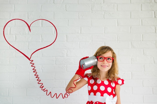 Photo happy girl with red vintage phone playing at home. valentines day concept