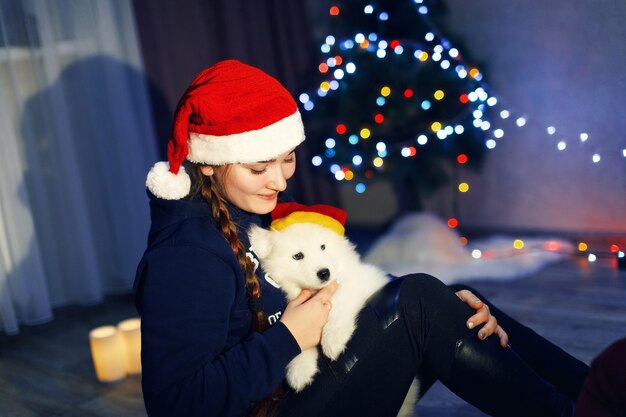 Photo happy girl with samoyed husky dog in christmas decorations