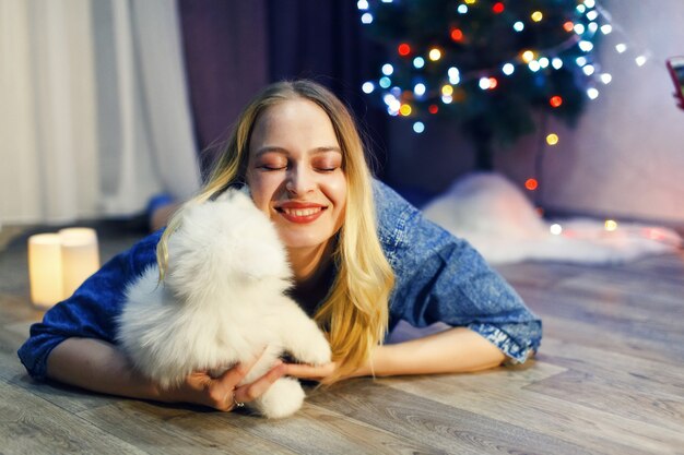 Foto ragazza felice con cane husky samoiedo nelle decorazioni natalizie