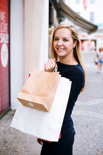 カメラを見ている買い物袋と幸せな女の子