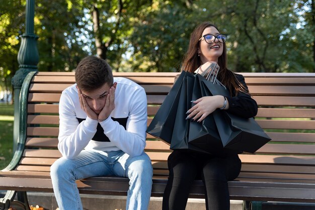 Happy girl with shopping bags and upset guy after shopping Spent all money on shopping