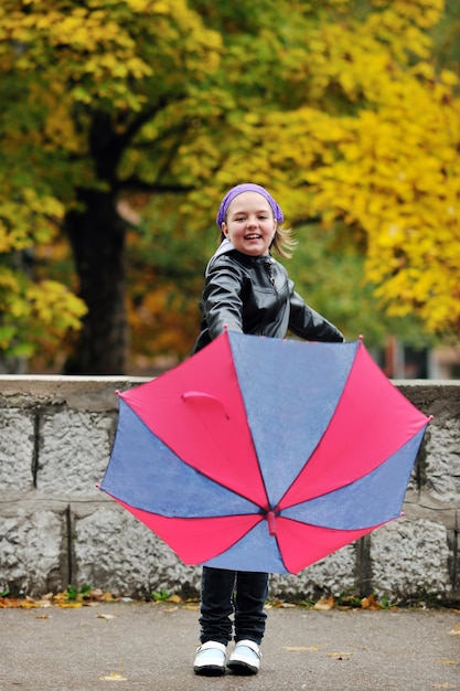 happy girl with umbrella outdoor in park on autumn season rain day