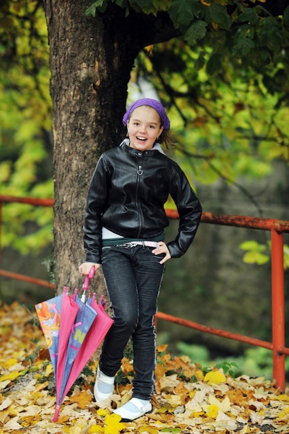 happy girl with umbrella outdoor in park on autumn season rain day