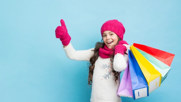 Foto ragazza felice con i sacchetti della spesa dell'abbigliamento di inverno