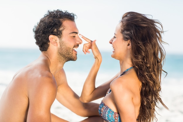 Happy girlfriend putting suncream on boyfriend