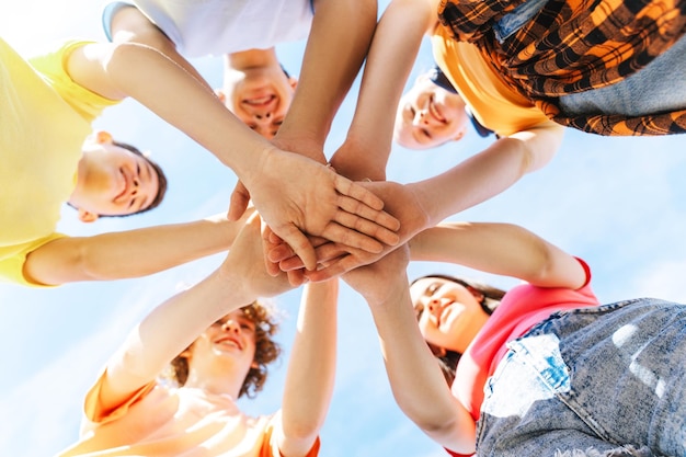 happy girls and boys holding hands together standing in circle outdoors