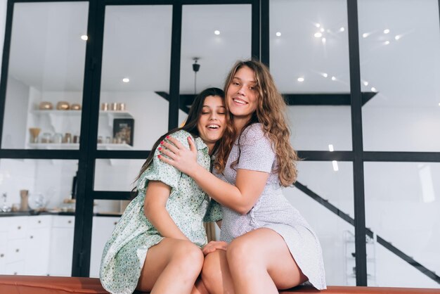 Happy girls embracing at home sitting on a couch in the living room