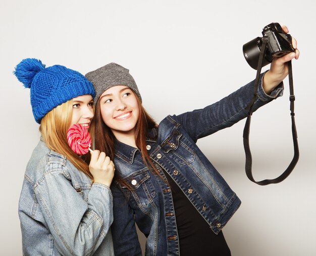 Happy girls friends taking some pictures, over grey background