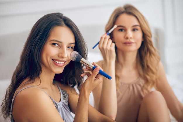 Happy girls. Pretty girls doing make up and looking happy