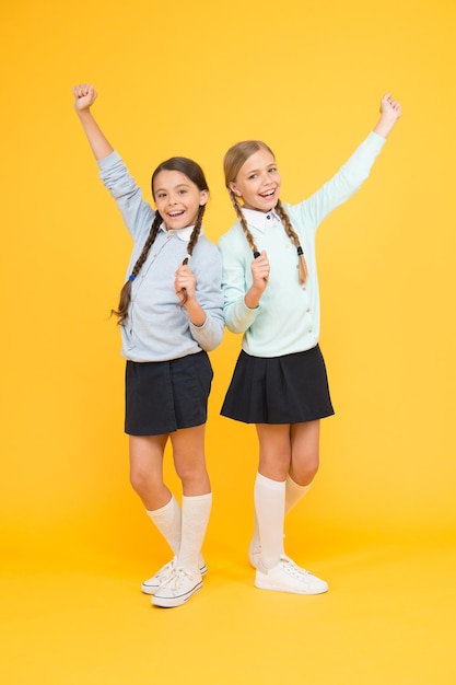 Happy girls in school uniform. smart little girls on yellow background. education concept. back to school. kid fashion. Friendship and sisterhood. knowledge day. childhood happiness. Just inspired.