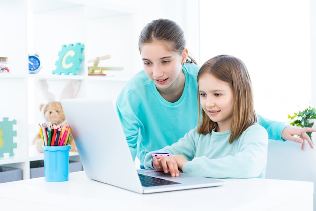 Happy girls working on computer in light room