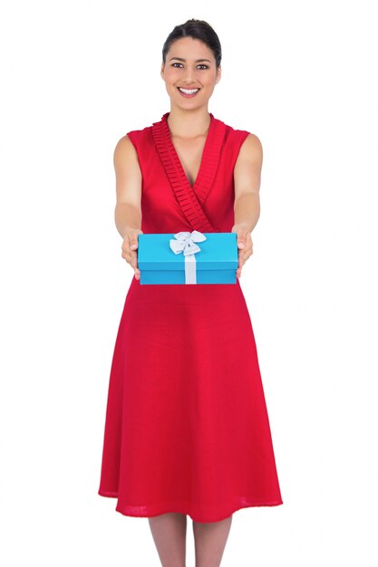 Happy glamorous model in red dress offering present