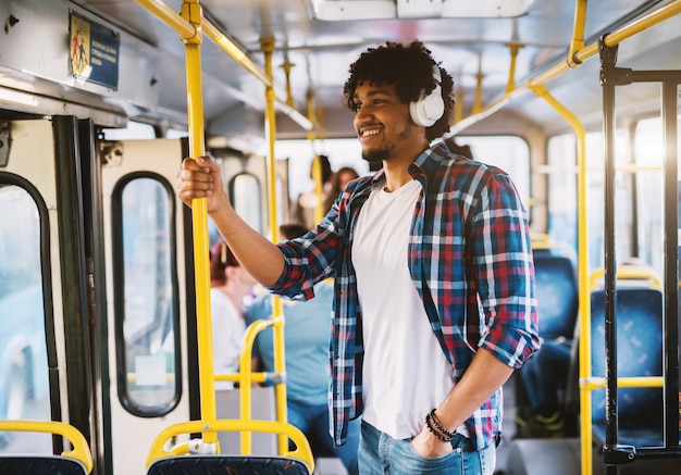 Happy glimlachte Afro-Amerikaan stond in een bus en luisterde naar de muziek via zijn telefoon.