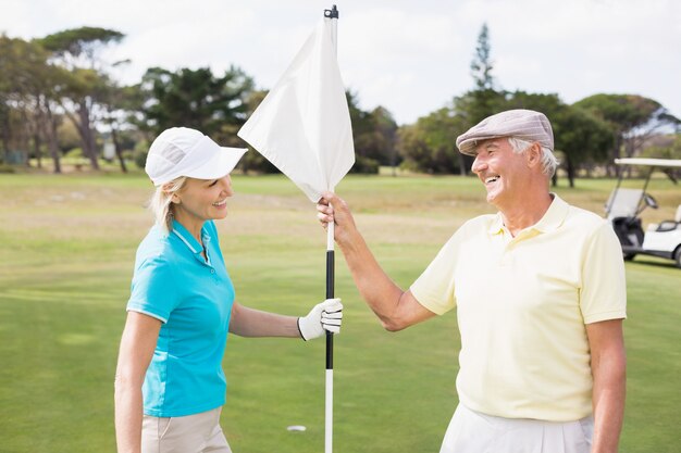 Happy golfer couple holding white flag