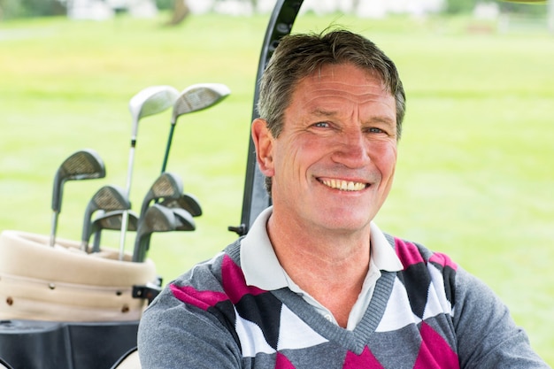 Happy golfer driving his golf buggy smiling at camera 