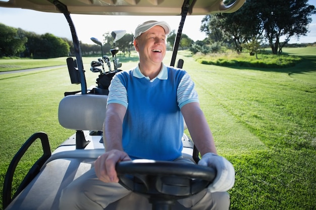 Happy golfer driving his golf buggy 