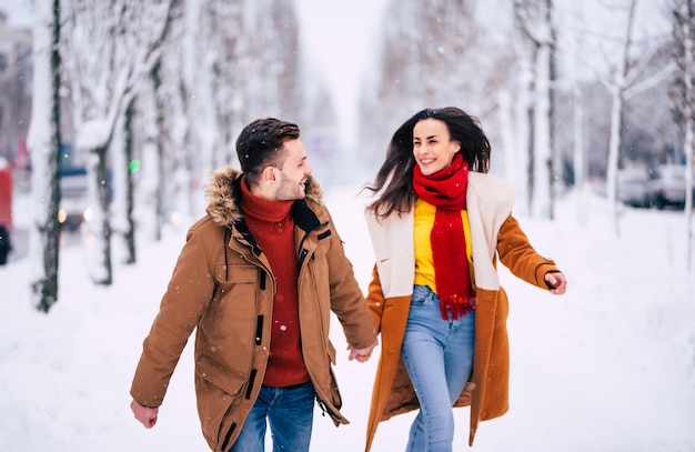 사랑하는 사람과 행복하고 좋은 하루. 사랑에 빠진 흥분한 젊은 부부가 겨울 도시 공원에서 함께 걷고 즐거운 시간을 보내고 있습니다