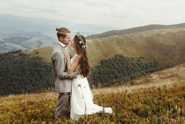 Happy gorgeous bride and groom hugging in sun light boho wedding couple luxury ceremony at mountains with amazing view space for text