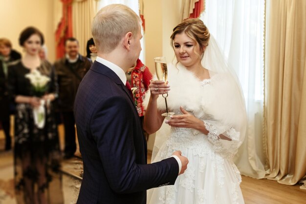 Felice splendida sposa e sposo alla moda che bevono champagne momento emotivo cerimonia ufficiale