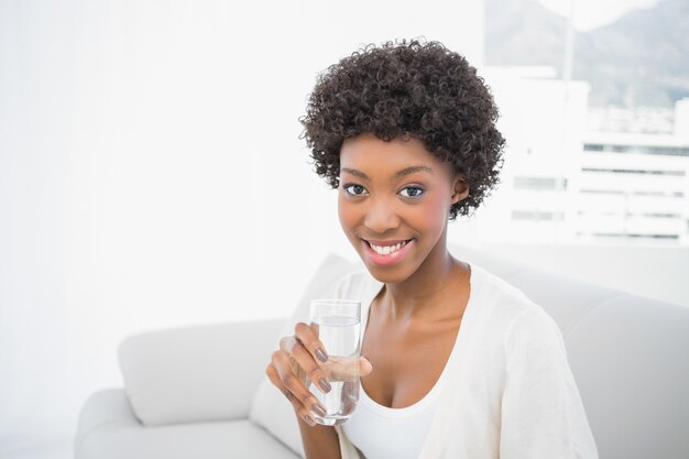 水のガラスを保持する幸せな豪華なブルネット