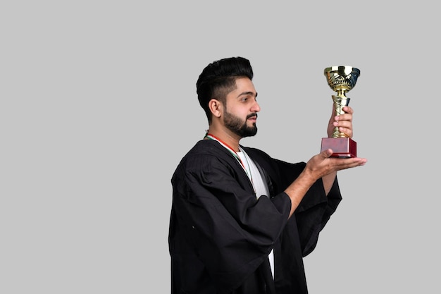 Happy graduate student holding gold trophy indian pakistani model