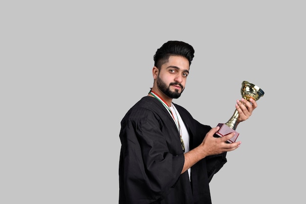 Happy graduate student holding gold trophy indian pakistani model