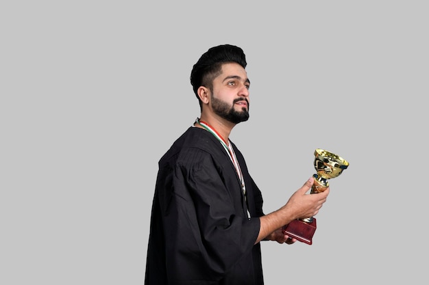 Happy graduate student holding gold trophy indian pakistani model